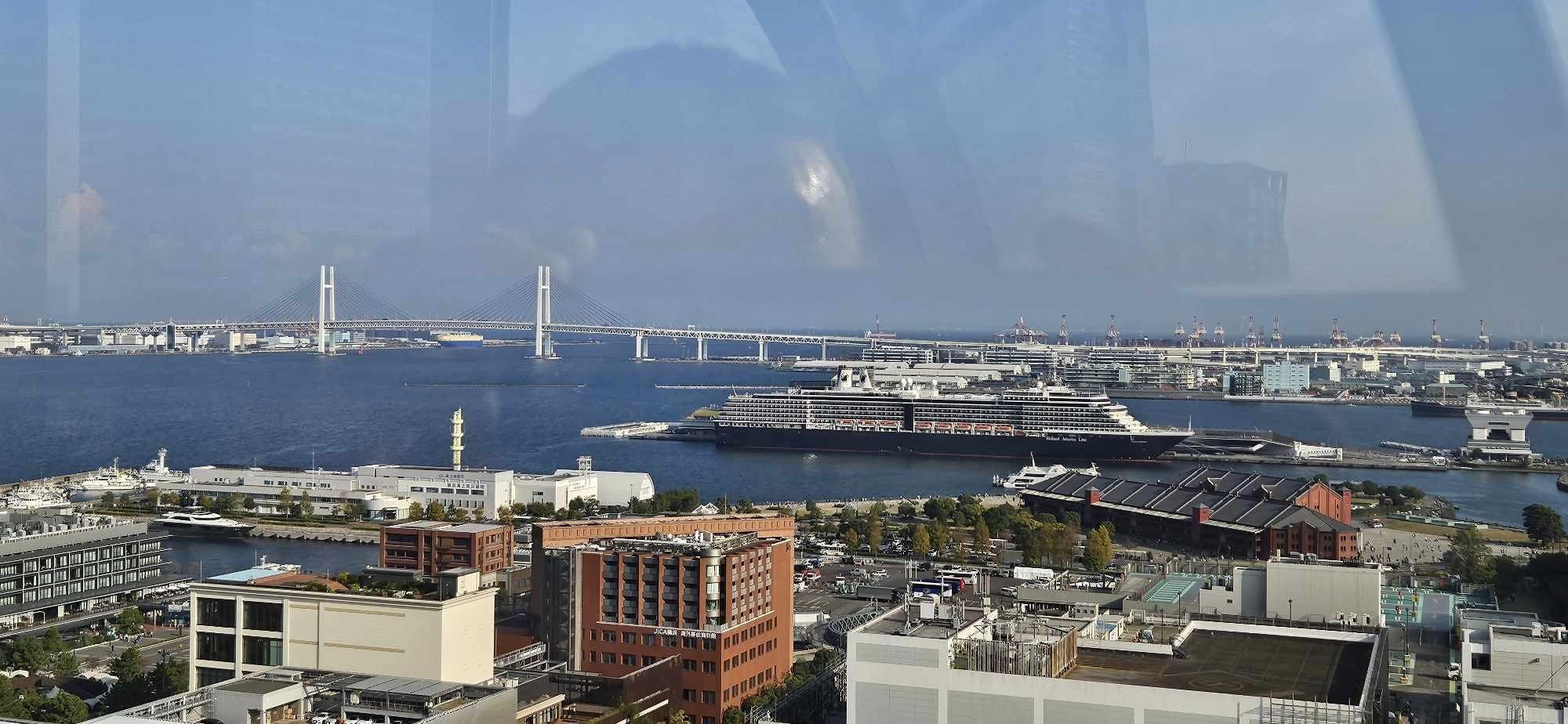 View from Yokohama Cosmo World ferris wheel over the water with a docked cruise ship, the Gundam Factory in the distance and bridge over the water
